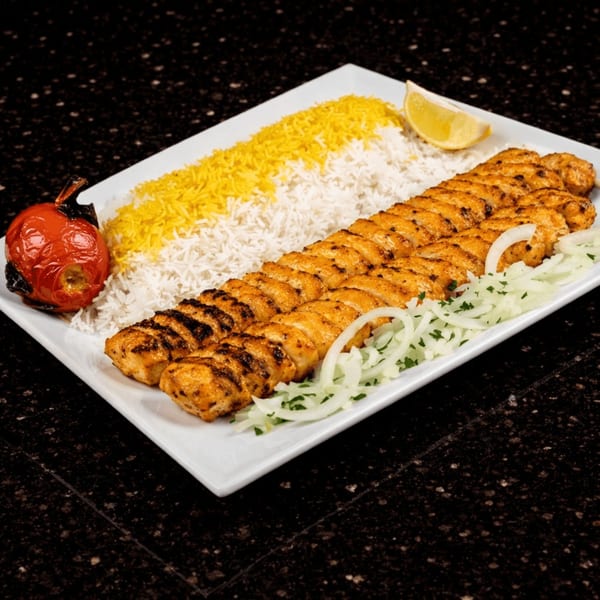 Persian chicken koobideh with white and saffron rice, grilled tomato, lemon, and onions.